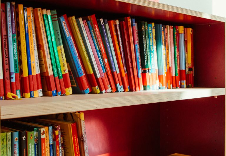 Rotes Bücherregal aus Holz mit vielen Kinderbüchern