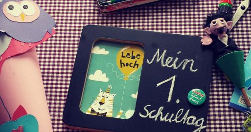 Ein buch mit der Aufschrift "Mein 1. Schultag" und eine bunte aus Pappe gebastelte Schultüte