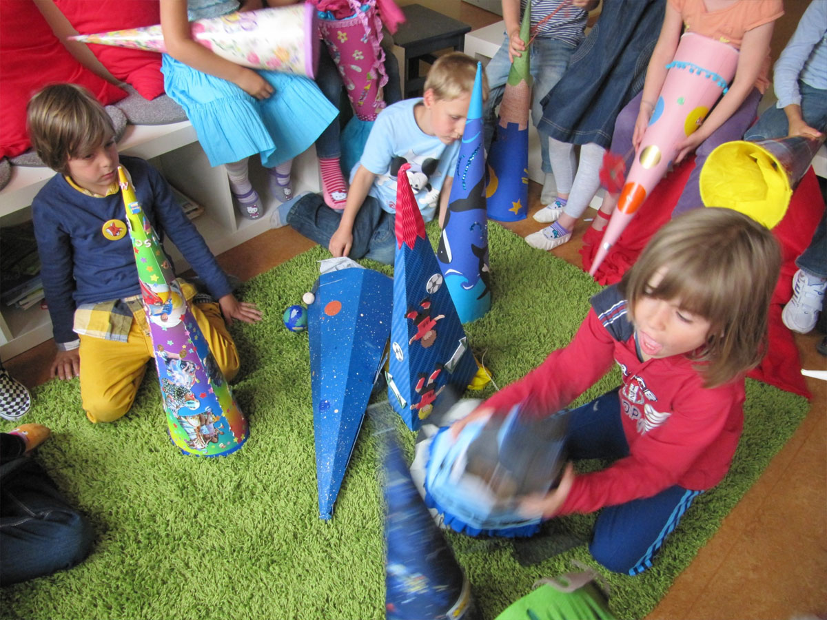 Eine Gruppe von Einschulungskindern spielen mit ihren bunten Schultüten und leeren sie aus